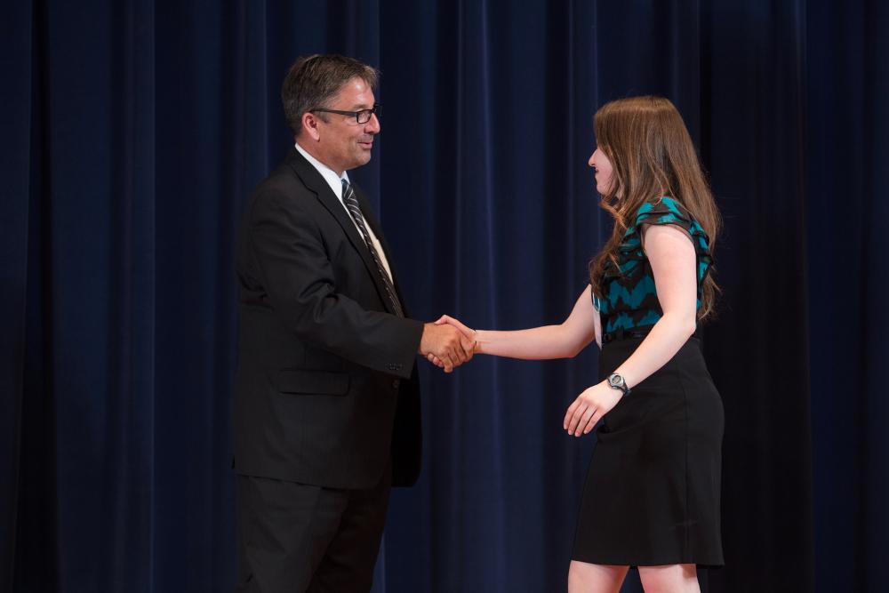 Doctor Smart shaking hands with an award recipient in a teal and black shirt
